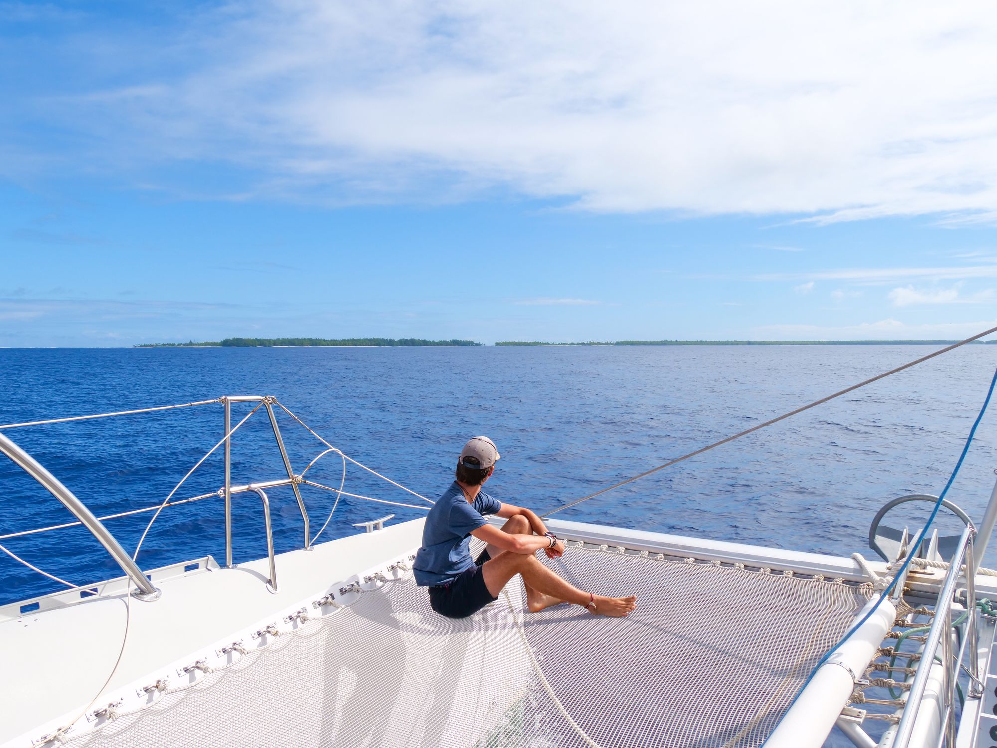 Jeune homme sur un catamaran qui regarde au large